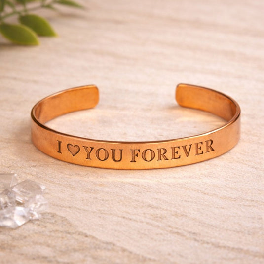 Rose gold bracelet with 'I ❤️ YOU FOREVER' engraving on a beige background