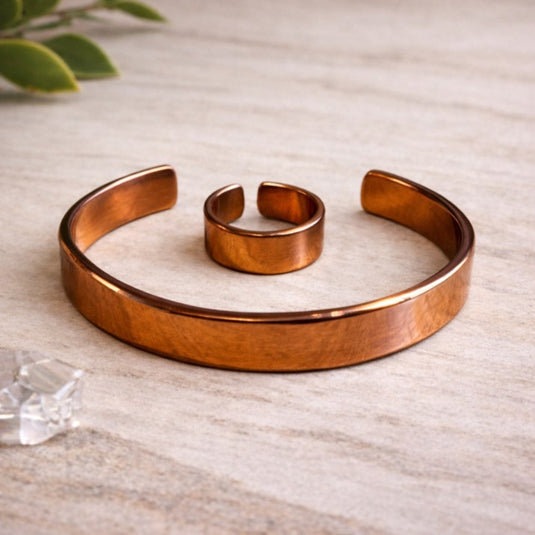 Copper bracelet on a light wooden surface with a plant in the corner