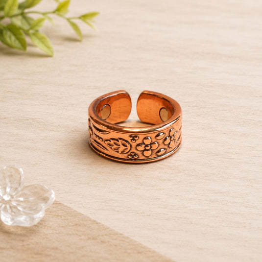 Copper bracelet with floral patterns on a light wooden surface