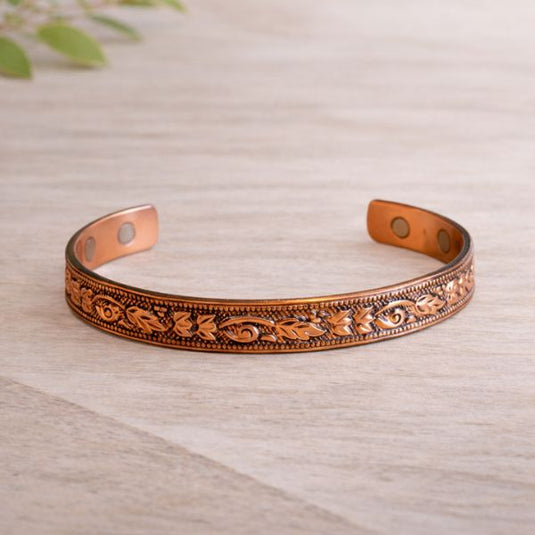 Decorative copper bracelet on a light wooden surface