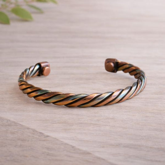 Twisted copper bracelet on a light wooden surface