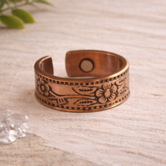 Copper bracelet with floral patterns on a light wooden surface