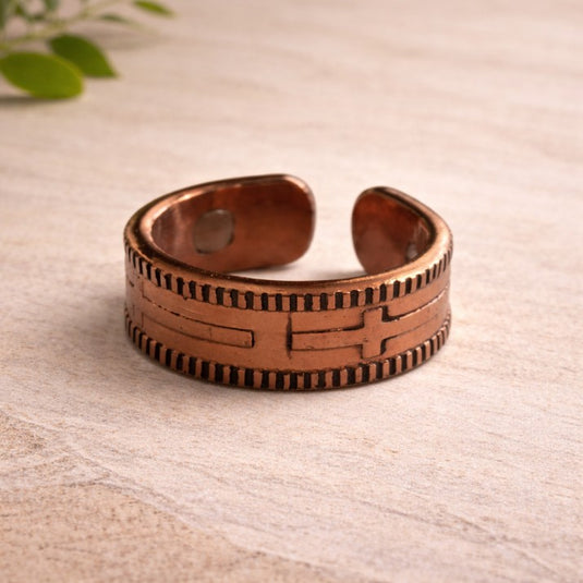 Copper ring with intricate design on a light wooden surface