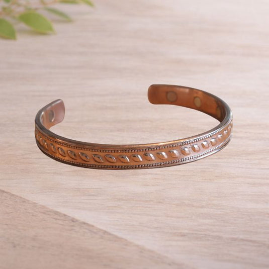 Copper bracelet with engraved pattern on a wooden surface